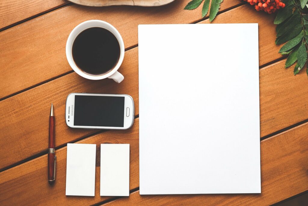 Eine Tasse Kaffee, Smartphone, Stift und Papier